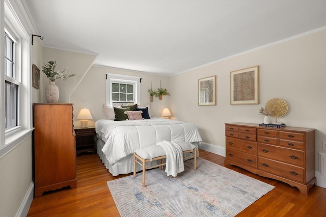 bedroom with wood finished floors, baseboards, and ornamental molding
