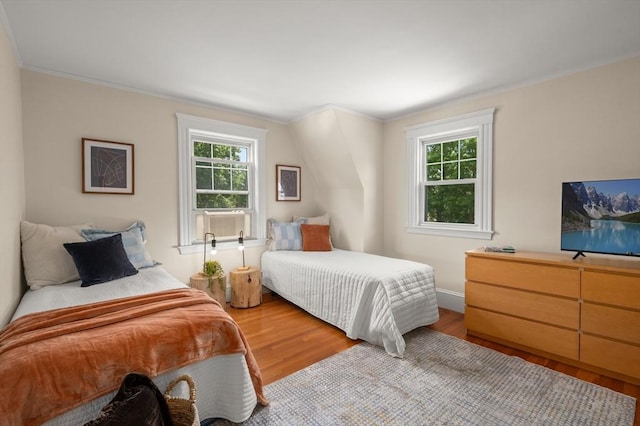 bedroom with wood finished floors, ornamental molding, and baseboards