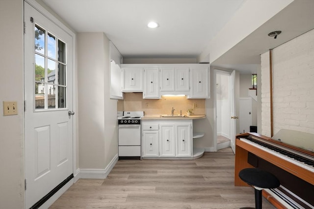 kitchen featuring white range, white cabinetry, a sink, light wood-style flooring, and light countertops