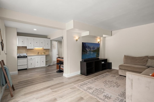 living room featuring light wood-type flooring, baseboards, and recessed lighting