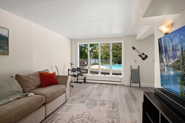 living room featuring a baseboard heating unit, light wood-style flooring, and baseboards