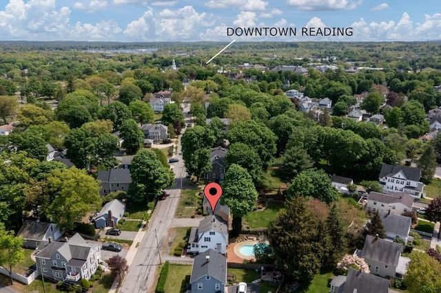 aerial view of property and surrounding area featuring nearby suburban area and a heavily wooded area