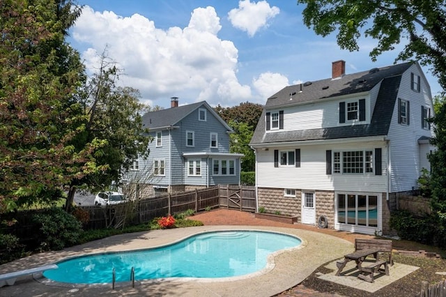 back of property featuring a fenced backyard, a gambrel roof, a chimney, and a patio area