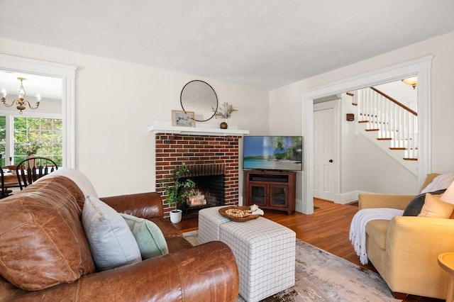 living area with a chandelier, wood finished floors, stairs, and a fireplace