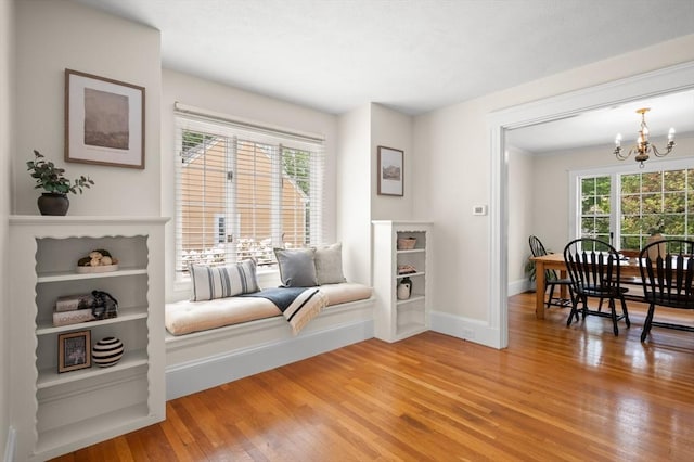 living area with a chandelier, light wood-type flooring, and baseboards