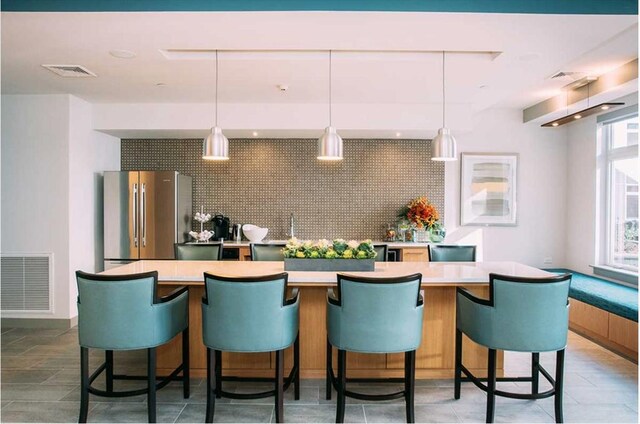 kitchen with freestanding refrigerator, visible vents, and a wealth of natural light