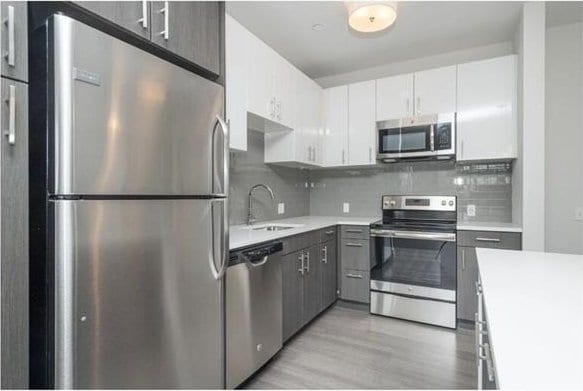 kitchen featuring light countertops, tasteful backsplash, a sink, light wood-style flooring, and stainless steel appliances