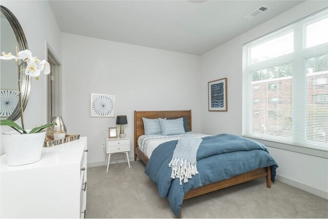 bedroom with baseboards, light colored carpet, and visible vents