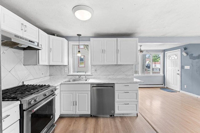 59 Harvard St, Everett, MA 02149 - kitchen featuring stainless steel appliances, under cabinet range hood, a baseboard radiator, a sink, and light wood-style floors