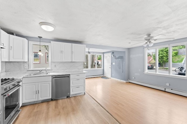 59 Harvard St, Everett, MA 02149 - kitchen featuring appliances with stainless steel finishes, baseboard heating, decorative backsplash, light wood finished floors, and ceiling fan