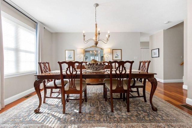 dining room with visible vents, wood finished floors, baseboards, and a chandelier