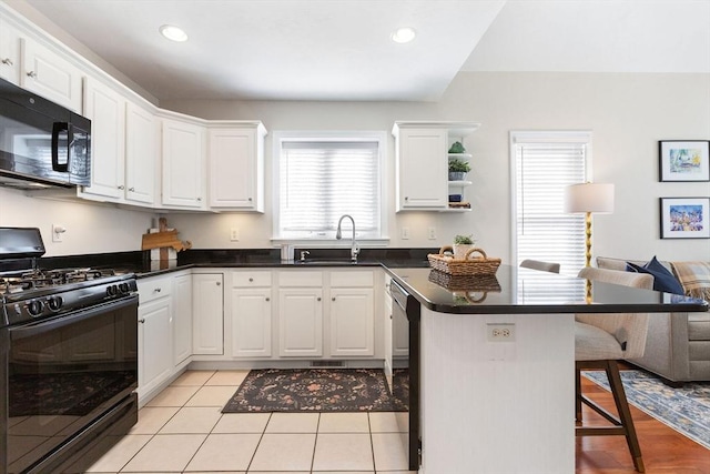 kitchen with a breakfast bar, a sink, black appliances, white cabinets, and dark countertops