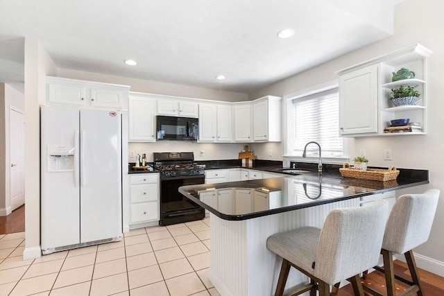 kitchen with dark countertops, black appliances, a peninsula, white cabinetry, and a sink