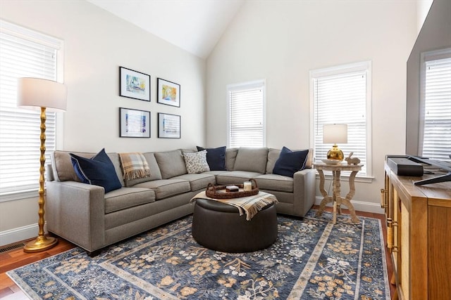 living room with lofted ceiling, wood finished floors, baseboards, and visible vents