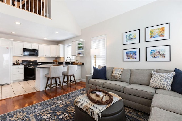 living room featuring recessed lighting, high vaulted ceiling, and light wood-style floors