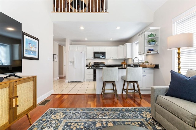 kitchen featuring visible vents, dark countertops, open floor plan, white fridge with ice dispenser, and black microwave