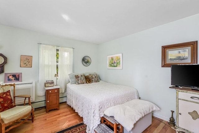bedroom featuring light wood finished floors, a baseboard radiator, and baseboards