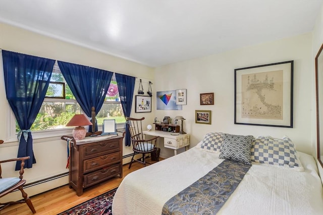 bedroom featuring wood finished floors and a baseboard heating unit