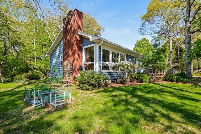 back of property with a chimney, a yard, a vegetable garden, and a deck
