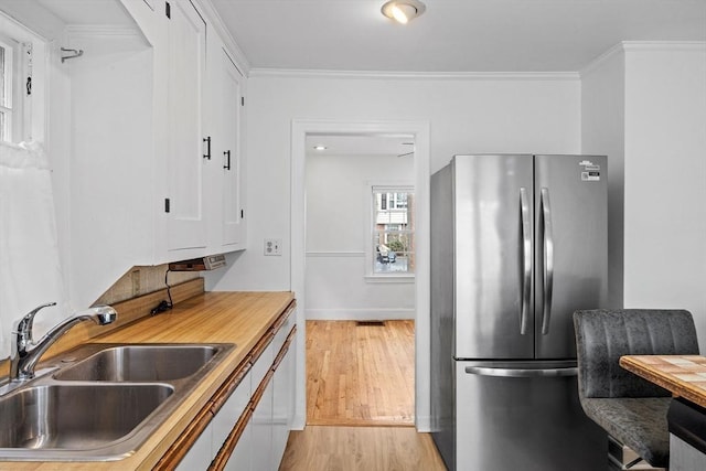 94 Clinton Rd, Weymouth, MA 02189 - kitchen with freestanding refrigerator, light wood-style flooring, white cabinets, light countertops, and ornamental molding