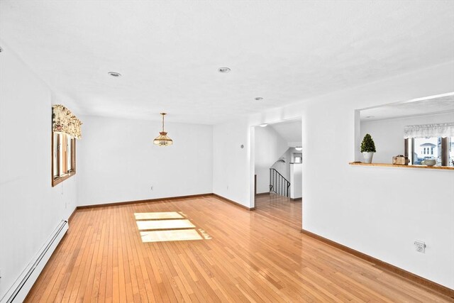 unfurnished living room featuring baseboards, a baseboard radiator, and light wood-style floors