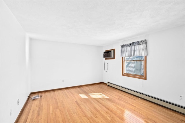 spare room featuring a textured ceiling, wood finished floors, baseboards, baseboard heating, and a wall mounted air conditioner