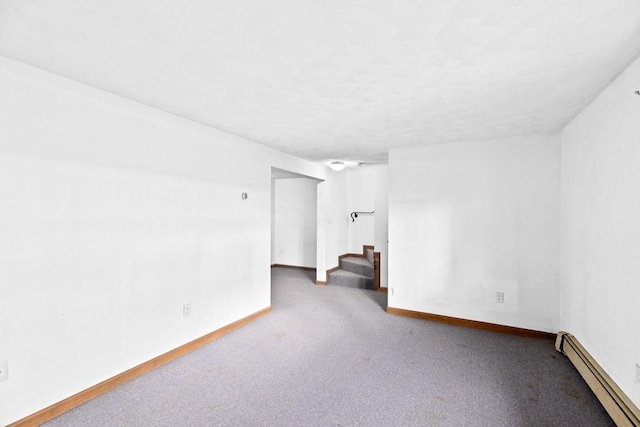 carpeted spare room with a baseboard heating unit, stairway, and baseboards