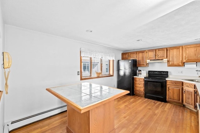 kitchen with a baseboard heating unit, black appliances, light wood-style floors, and under cabinet range hood