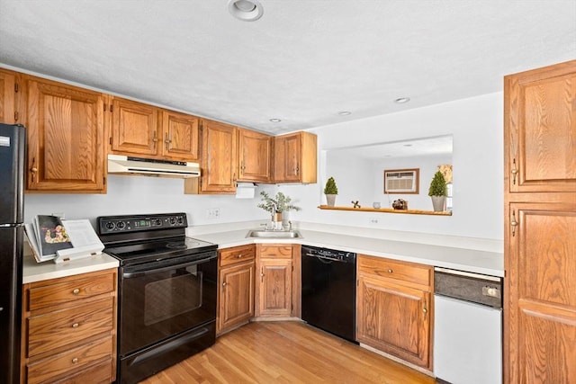 kitchen with black appliances, brown cabinetry, light countertops, and under cabinet range hood