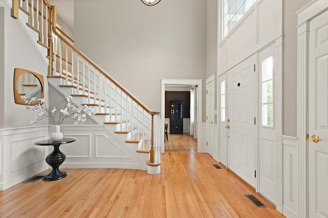 45 Anselm Way, Sudbury, MA 01776 - foyer featuring a decorative wall, stairway, wood finished floors, a high ceiling, and wainscoting