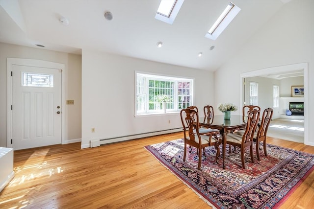 18 Curve Hill Rd, Yarmouth, MA 02664 - dining room with a baseboard radiator, a skylight, light wood-style floors, high vaulted ceiling, and a glass covered fireplace