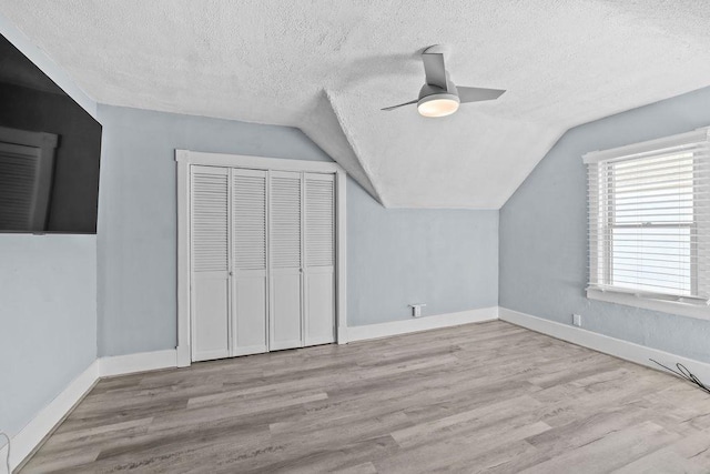 bonus room with a textured ceiling, ceiling fan, lofted ceiling, and light wood-type flooring