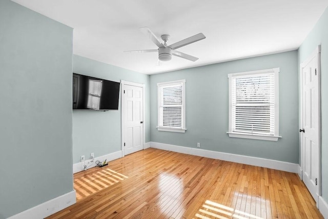 empty room featuring a wealth of natural light, hardwood / wood-style floors, and ceiling fan