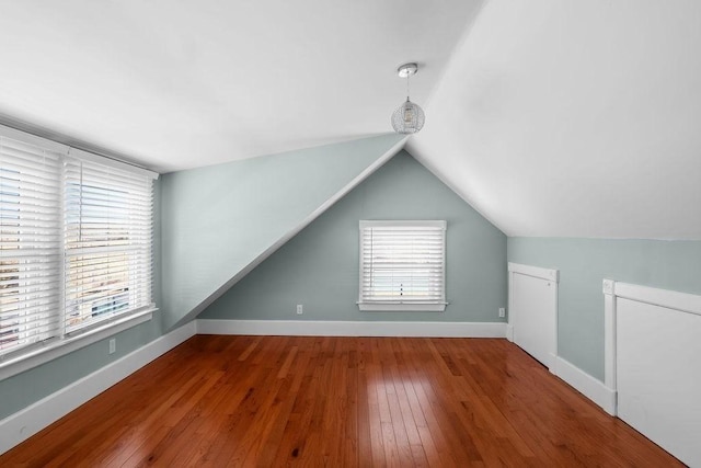 additional living space with hardwood / wood-style floors and vaulted ceiling