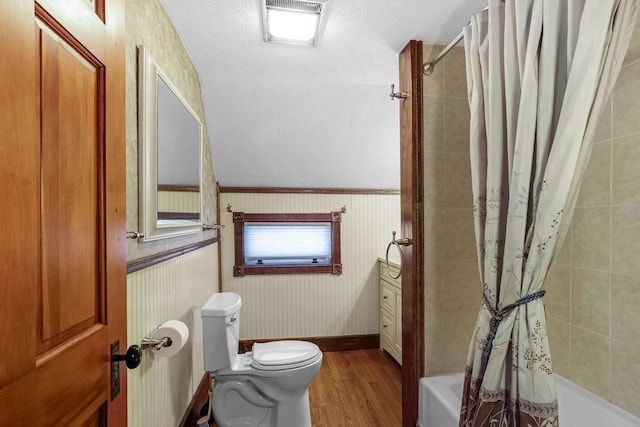 bathroom with hardwood / wood-style flooring, shower / bath combo, toilet, and a textured ceiling