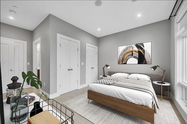 bedroom featuring multiple windows, two closets, and light wood-type flooring