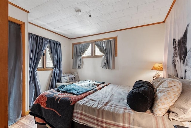 bedroom with crown molding and wood finished floors