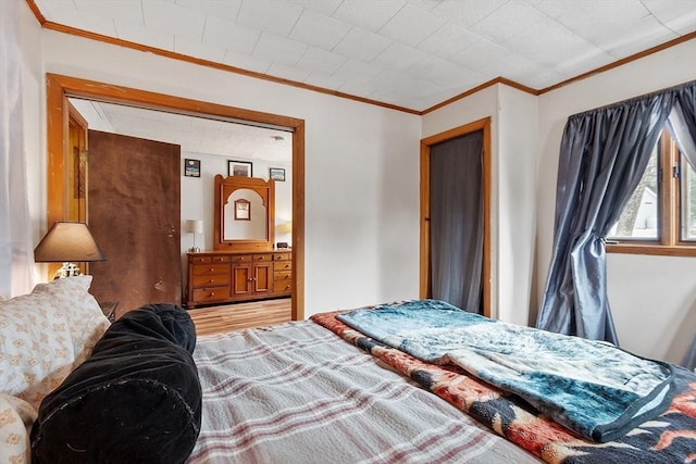 bedroom with wood finished floors and ornamental molding