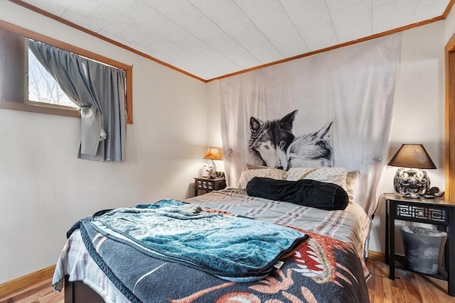 bedroom with crown molding, wood finished floors, and baseboards