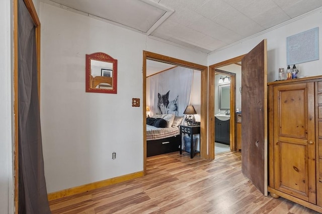 corridor with a sink, baseboards, and light wood finished floors