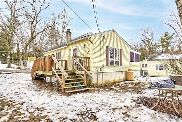 back of property with a wooden deck, a chimney, and fence