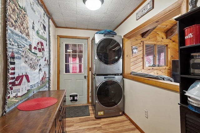 laundry area with baseboards, light wood-style flooring, crown molding, and stacked washer / dryer