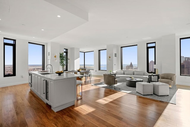 kitchen with sink, light wood-type flooring, a breakfast bar, and a center island with sink