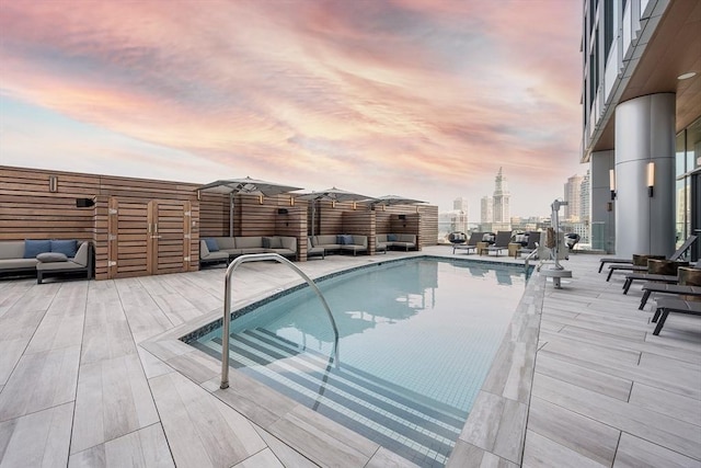 pool at dusk featuring outdoor lounge area and a patio