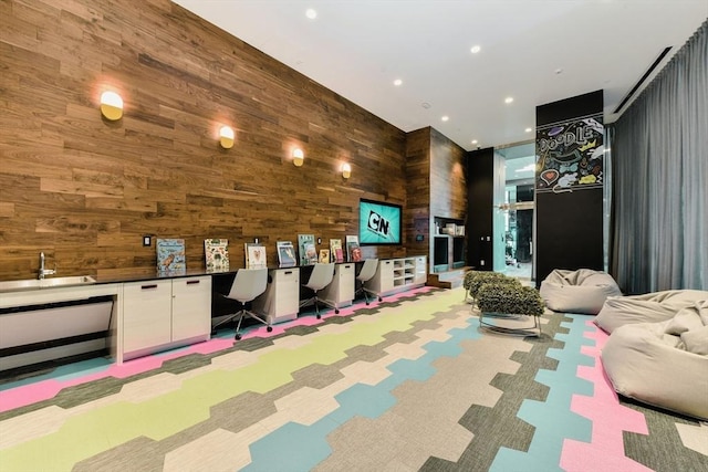 recreation room featuring light carpet, built in desk, and wooden walls