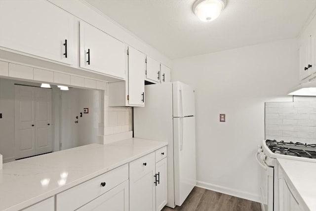 kitchen featuring under cabinet range hood, wood finished floors, white cabinetry, white appliances, and decorative backsplash