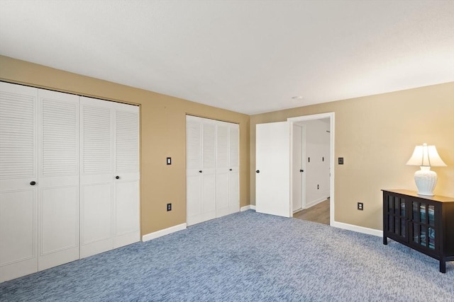 unfurnished bedroom featuring carpet flooring, baseboards, and multiple closets