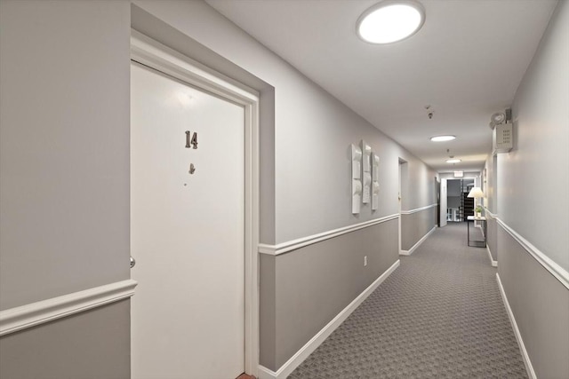 hallway featuring carpet and baseboards