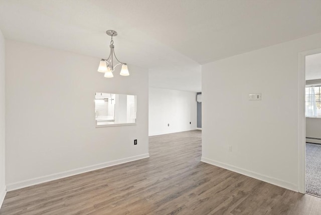 unfurnished room with a notable chandelier, baseboards, and wood finished floors