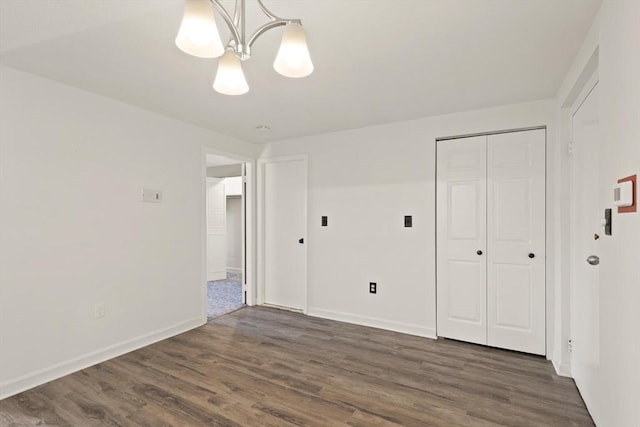 unfurnished bedroom with dark wood finished floors, baseboards, and a closet